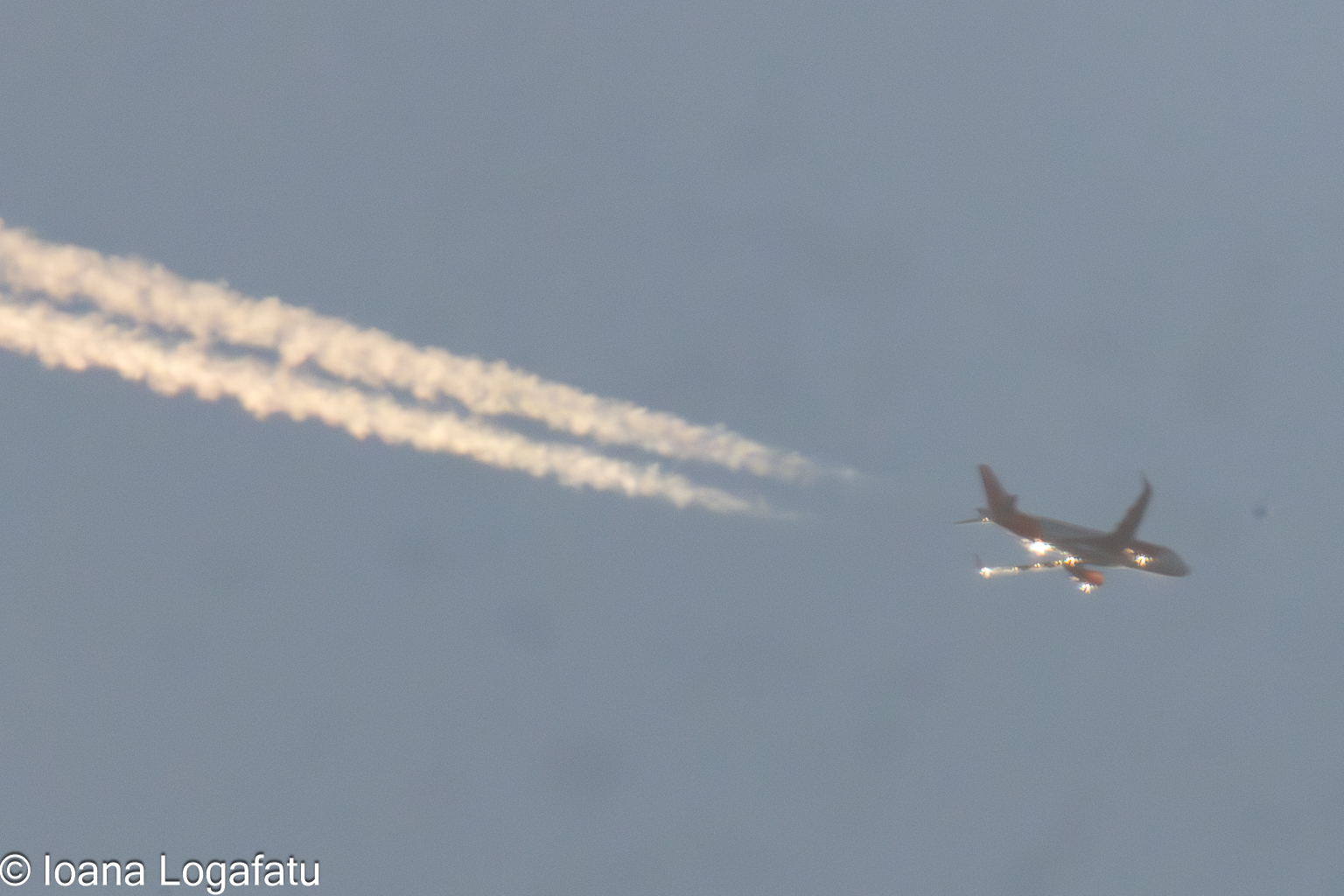 Plane soaring high with trails across the sky